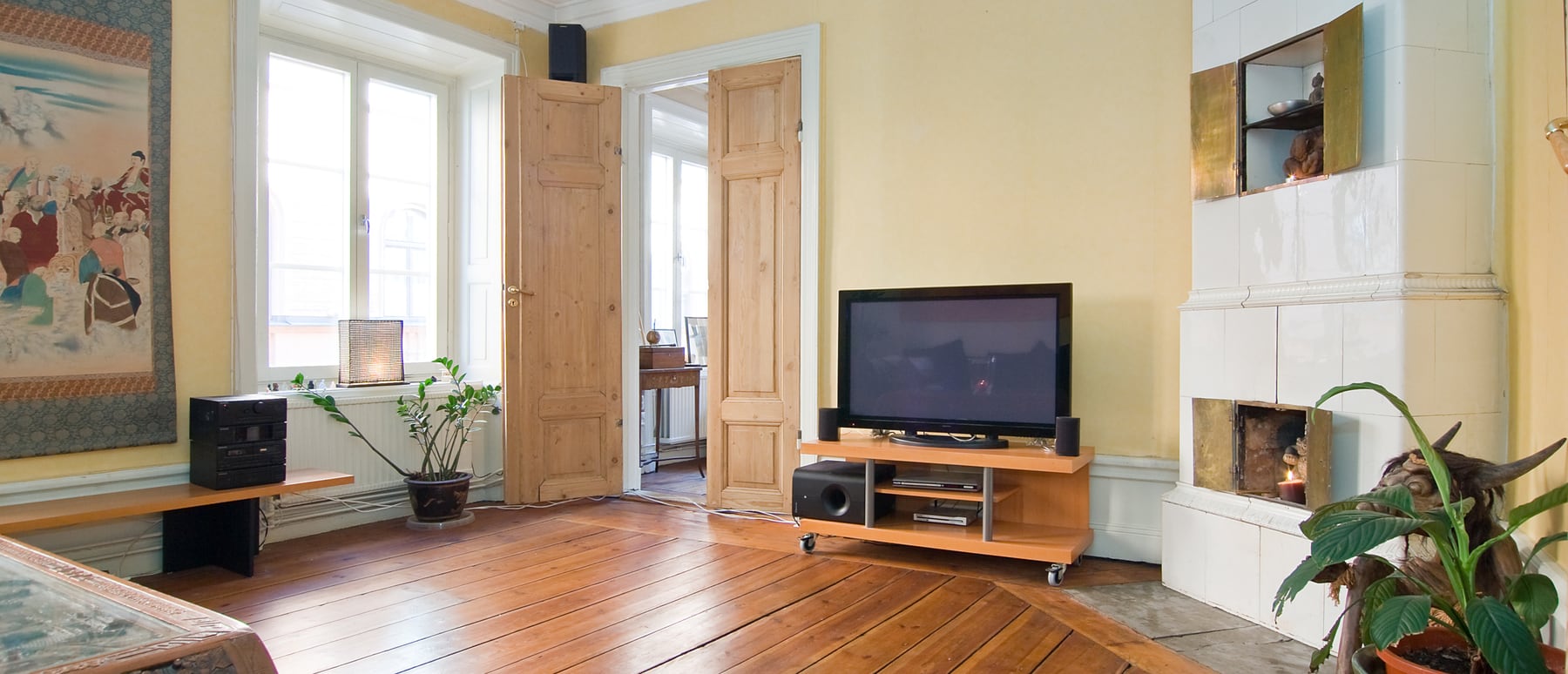Wohnzimmer mit schwedsichem SVEA Kachelofen, Holzboden und warmer Atmosphäre